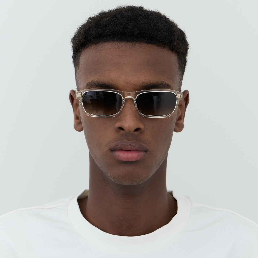 Model wearing transparent acetate sunglasses with green lenses.